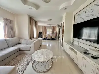 Spacious living room with elegant decor and large TV, perfect for modern living.