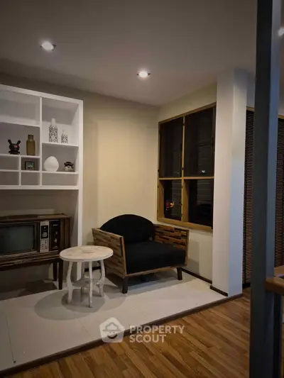 Cozy living room with vintage TV, stylish armchair, and elegant shelving unit.