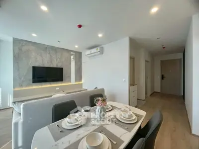 Modern living room with stylish dining area and wall-mounted TV in open layout apartment.