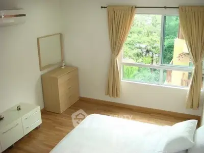 Bright bedroom with large window and wooden flooring, offering a serene garden view.