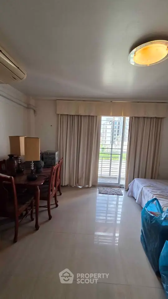 Spacious living room with elegant dining set and large window offering natural light.