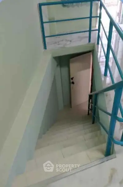 Modern staircase with blue railings leading to a door, ideal for contemporary homes.