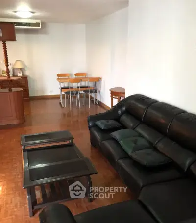 Spacious living room with leather sofa and wooden furniture, perfect for relaxation.