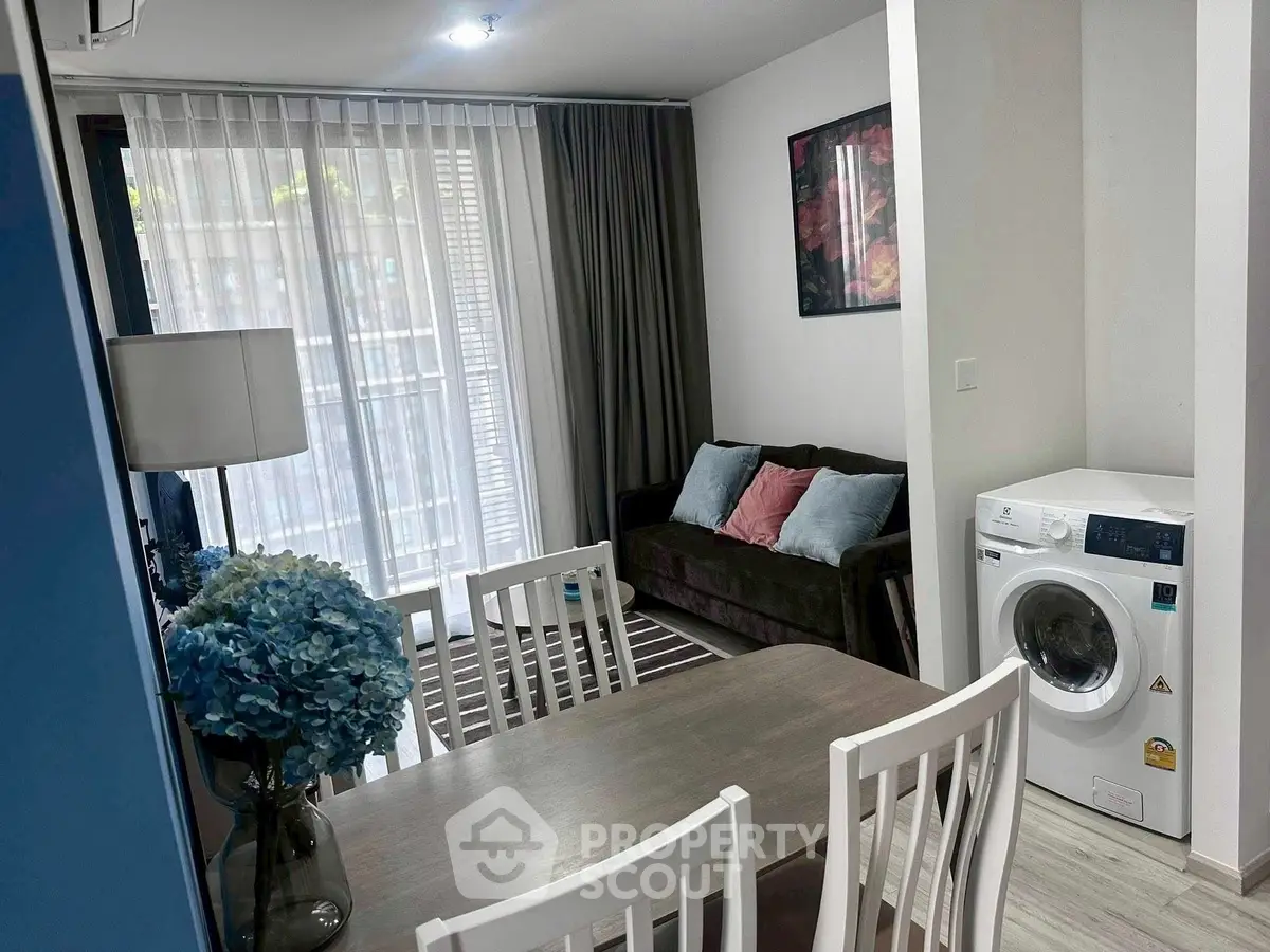 Chic modern living room with dining area and washing machine, featuring stylish decor and natural light.