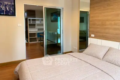 Modern bedroom with wooden flooring and sliding glass doors leading to a study area.