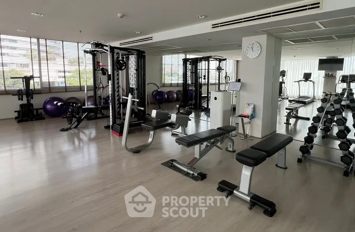 Spacious modern gym with state-of-the-art equipment and mirrored walls in a luxury building.