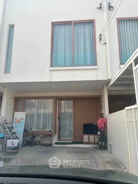 Modern townhouse exterior with large windows and driveway in a suburban setting.