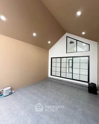 Spacious modern room with high ceiling and large windows, perfect for versatile use.