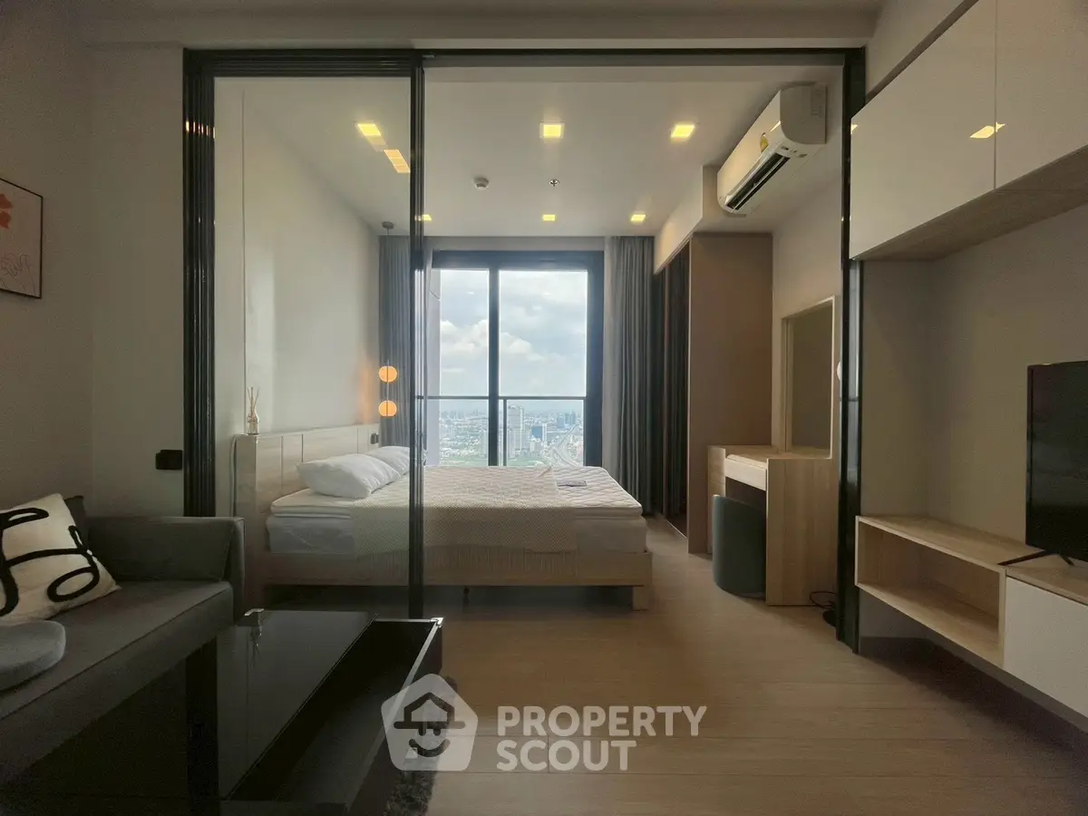 Modern apartment with glass partition, cozy living room, and stunning city view from the bedroom.