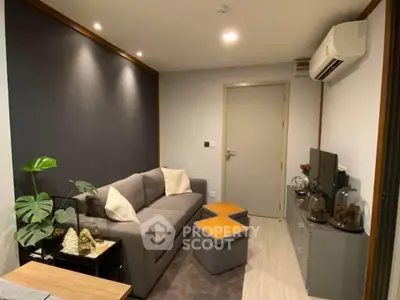 Modern living room with sleek gray sofa, stylish decor, and air conditioning in a cozy apartment.