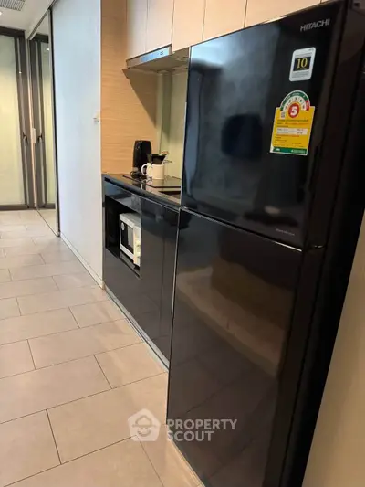 Modern kitchen with sleek black fridge and built-in appliances in a stylish apartment.