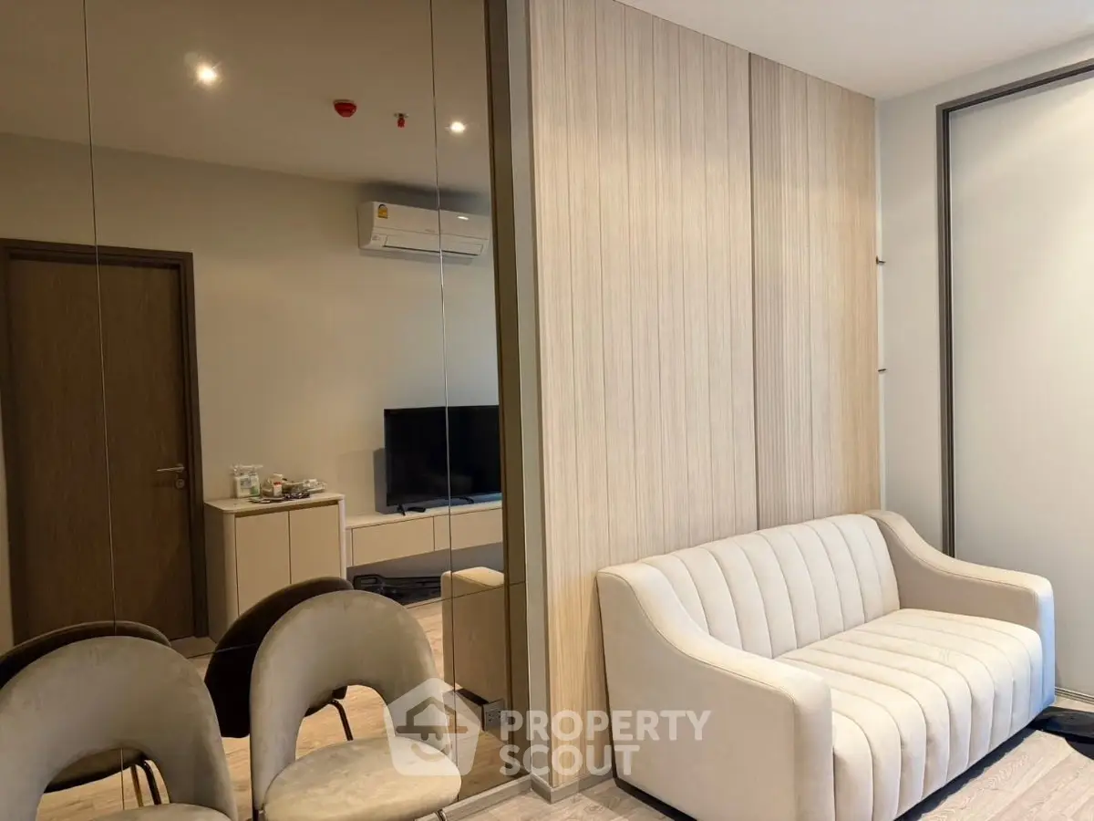 Modern living room with elegant sofa and mirrored wall, featuring stylish decor and ambient lighting.