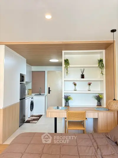 Modern studio apartment with integrated kitchen and cozy dining area, featuring stylish decor and efficient use of space.