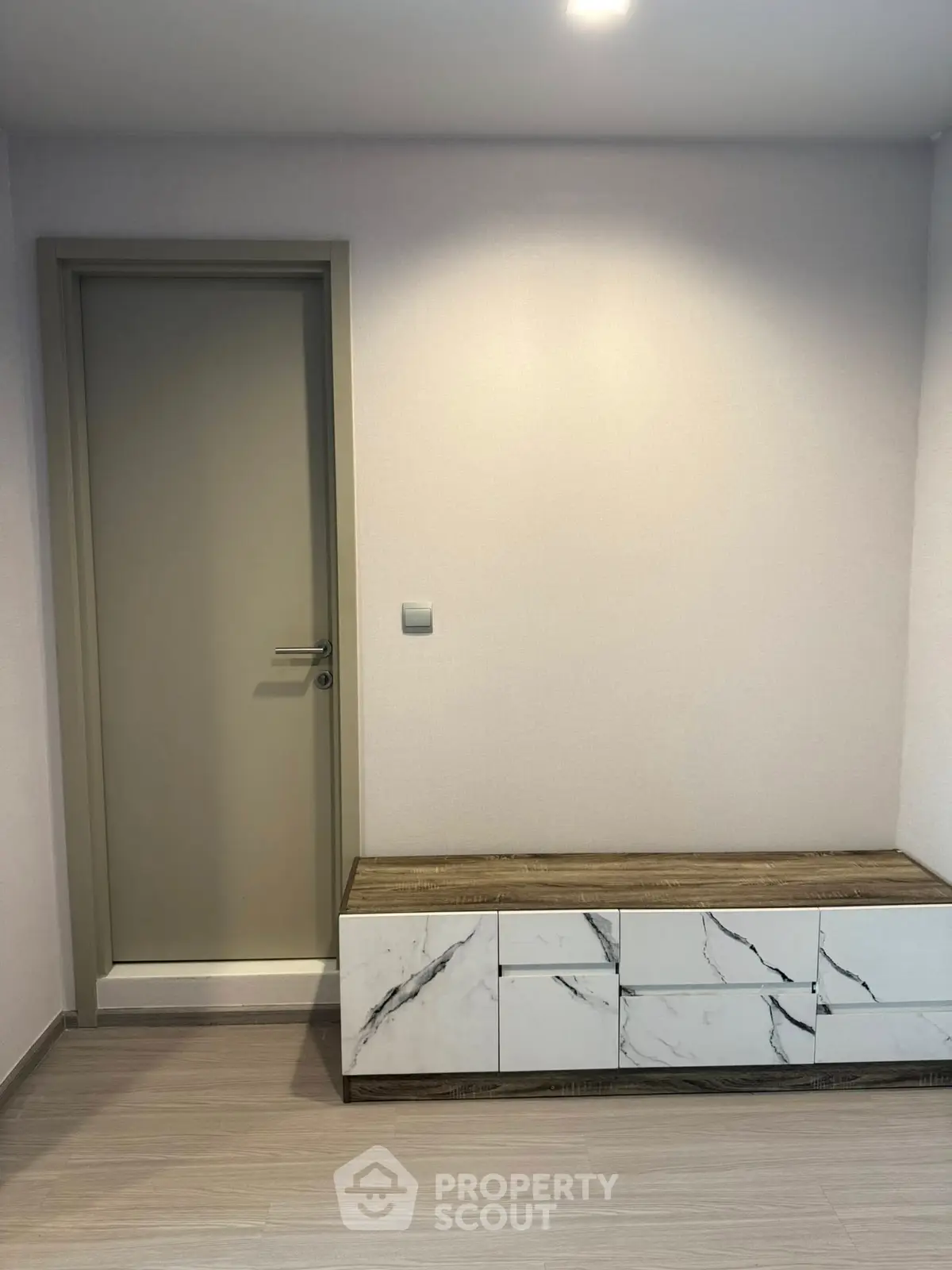 Modern minimalist interior with sleek door and marble-accented storage unit.