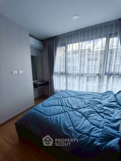 Cozy bedroom with large window and modern decor in a stylish apartment.