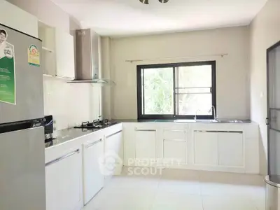 Modern kitchen with sleek white cabinetry and large window for natural light.