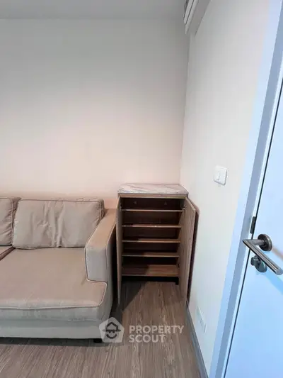 Cozy living room corner with beige sofa and wooden cabinet on sleek flooring.