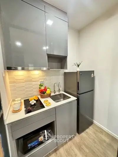 Modern compact kitchen with sleek grey cabinets and stainless steel appliances
