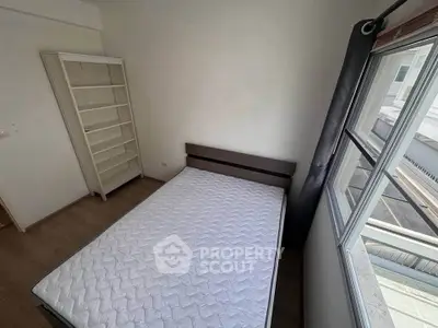 Cozy bedroom with large window and empty bookshelf, perfect for personalization.