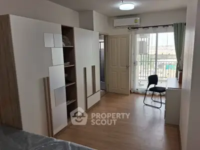 Spacious modern bedroom with balcony access and ample storage in urban apartment.