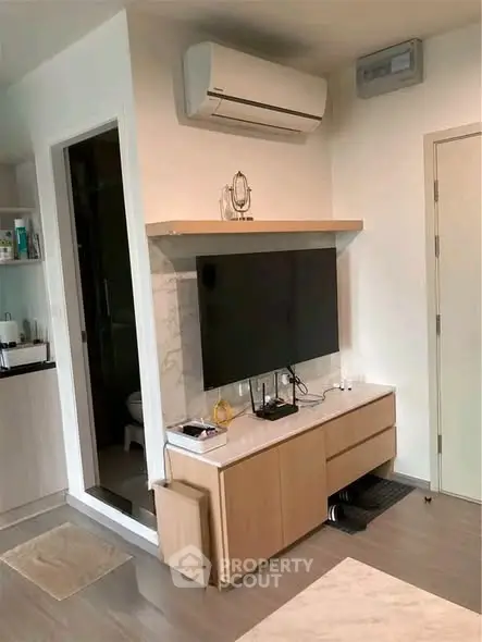 Modern living room with sleek TV setup and air conditioning unit, showcasing contemporary interior design.