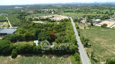 Expansive aerial view of lush green land with road access, ideal for development opportunities.