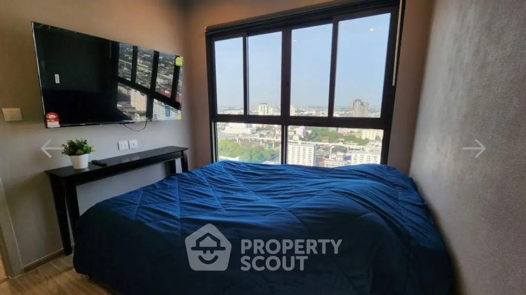 Modern bedroom with large window offering stunning city view and wall-mounted TV.