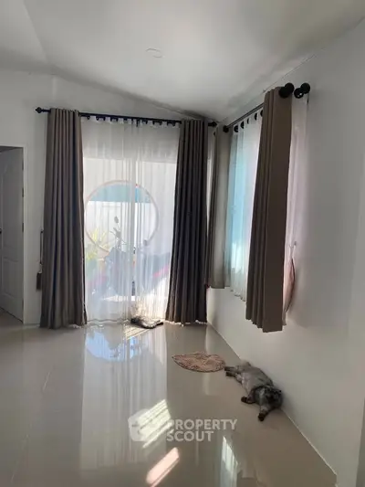 Spacious living room with large windows and elegant curtains, perfect for natural light.