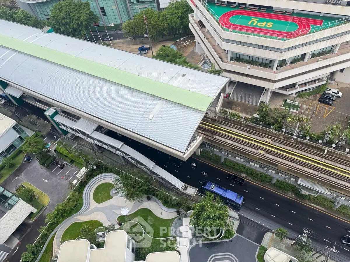 Aerial view of modern urban landscape with train station and green rooftop garden.