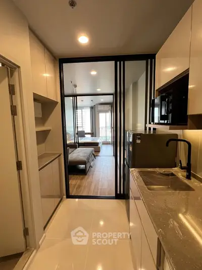 Modern open-layout kitchen with sleek cabinetry and view into stylish living room
