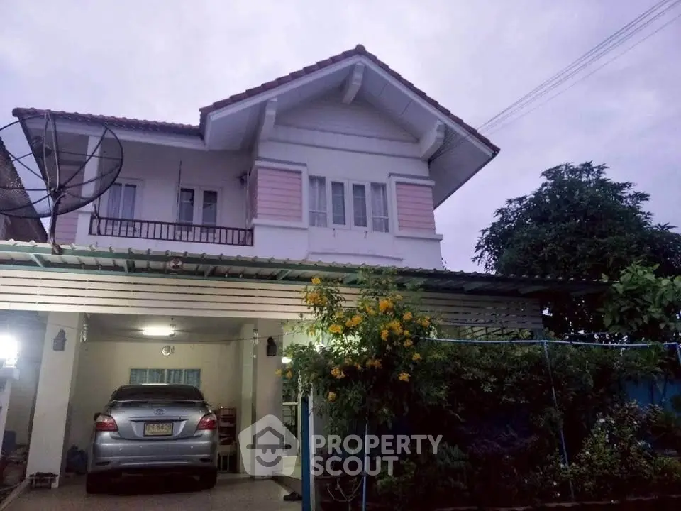 Charming two-story house with carport and lush garden in a serene neighborhood.