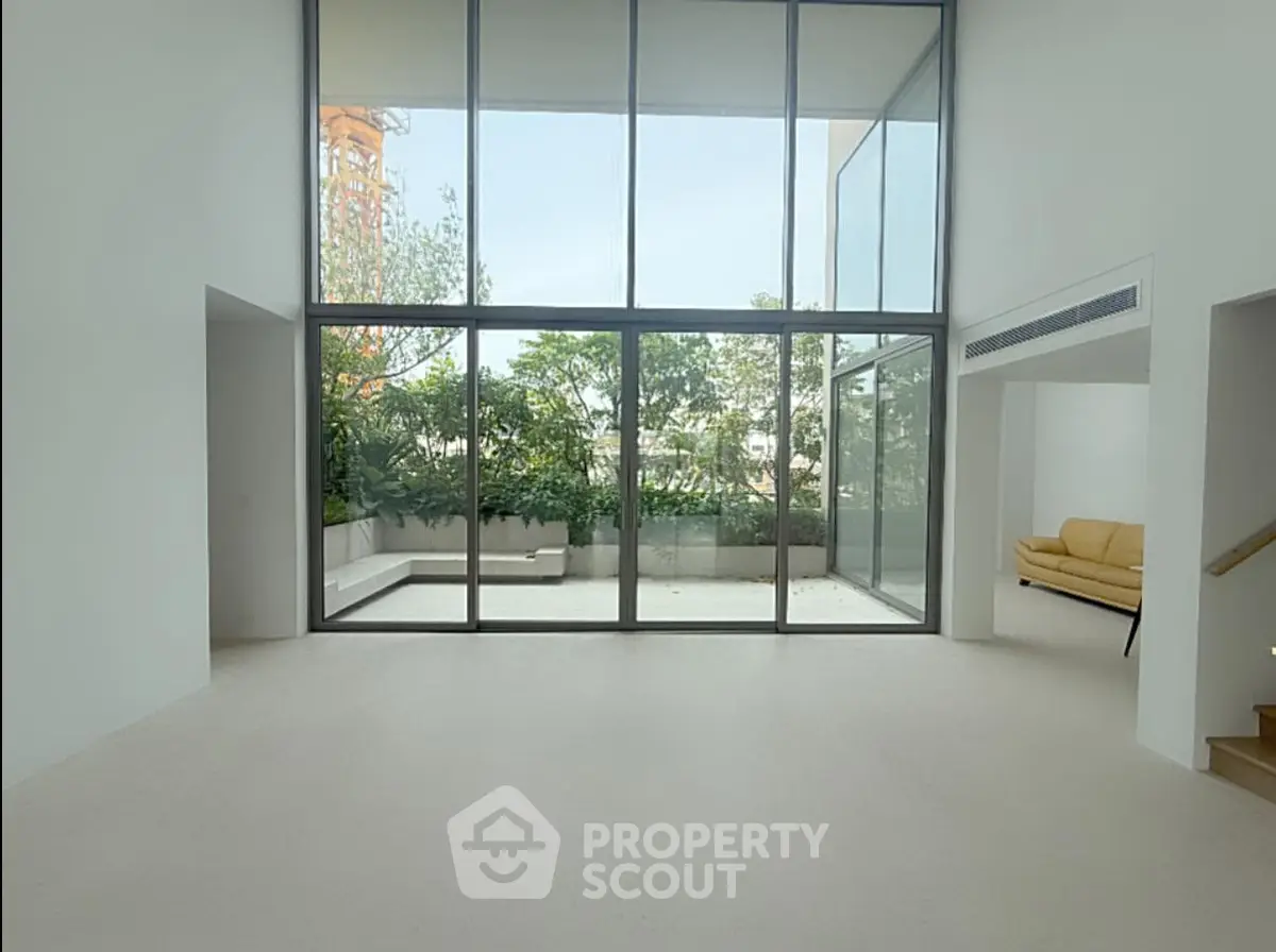 Spacious modern living room with floor-to-ceiling windows and garden view