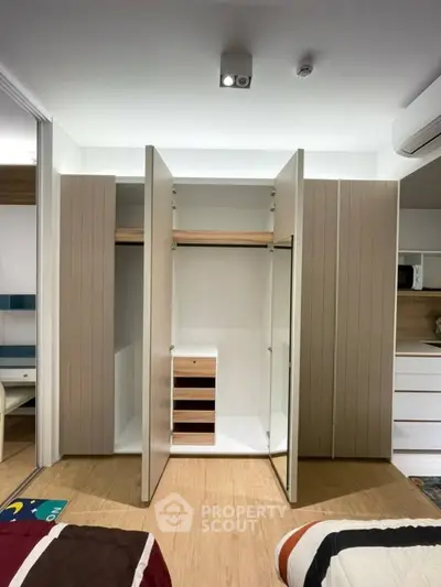 Spacious bedroom with modern built-in wardrobe and sleek wooden flooring.