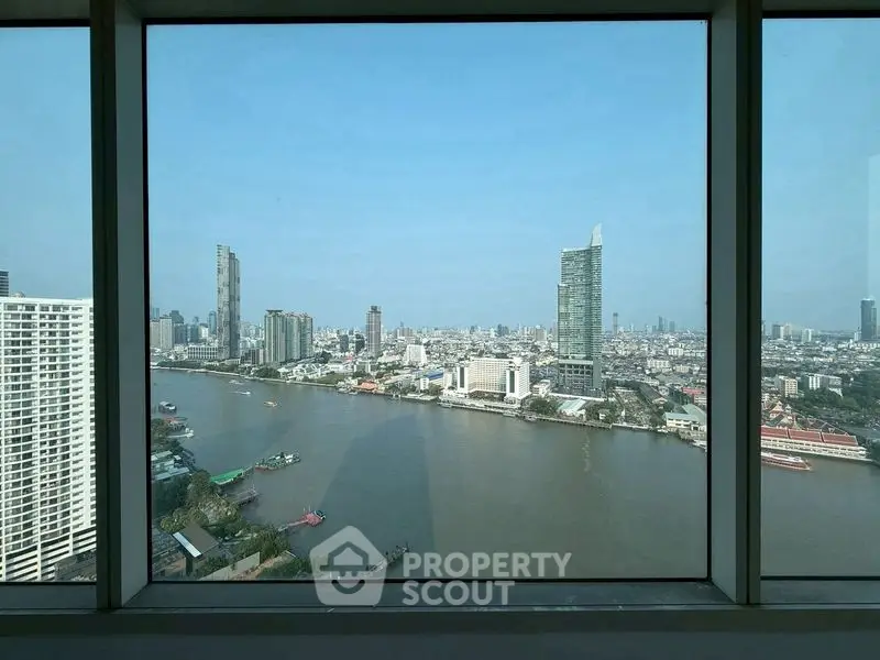 Stunning cityscape view from high-rise window overlooking river and skyline.