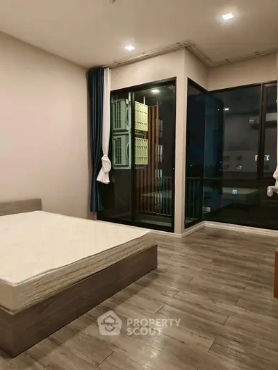 Modern bedroom with large windows and wooden flooring