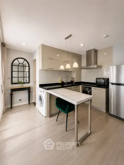 Modern kitchen with sleek design, featuring stainless steel appliances and a washing machine under the counter.