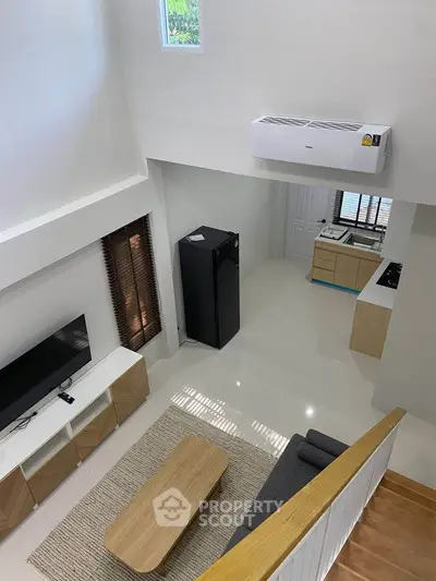 Modern living room with high ceiling, sleek furniture, and open kitchen layout.