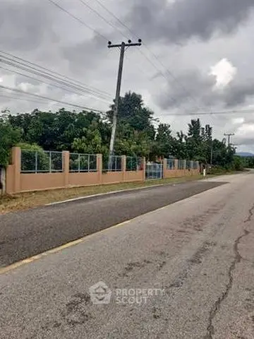 Scenic roadside view with lush greenery and fenced property