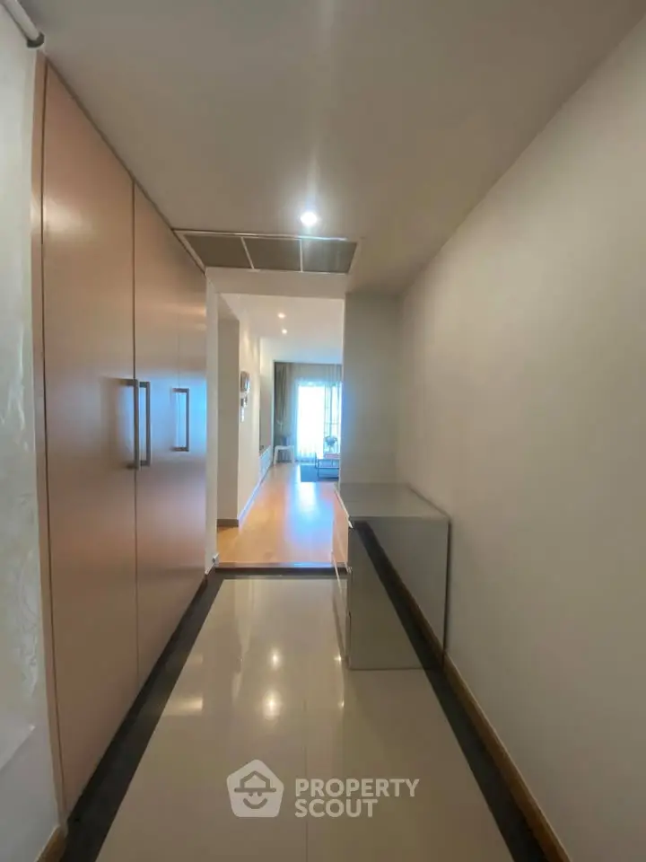 Spacious hallway leading to a bright living room with modern decor and large windows.