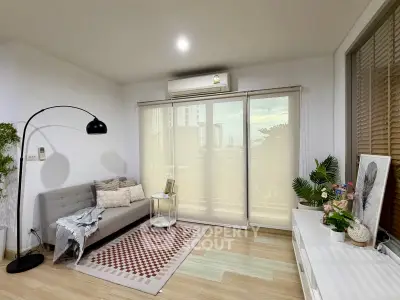Modern living room with stylish decor and large window offering natural light and city view.