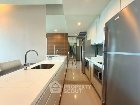 Modern kitchen with sleek appliances and mirrored backsplash in luxury apartment