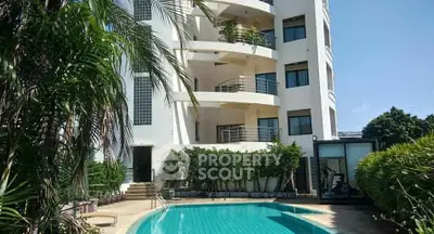 Luxurious apartment building with pool and lush greenery