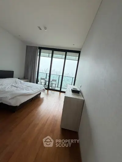 Spacious bedroom with stunning city view and balcony access in modern apartment.