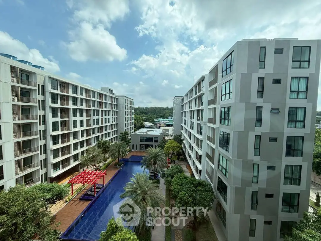 Modern apartment complex with pool and lush greenery under a bright blue sky.