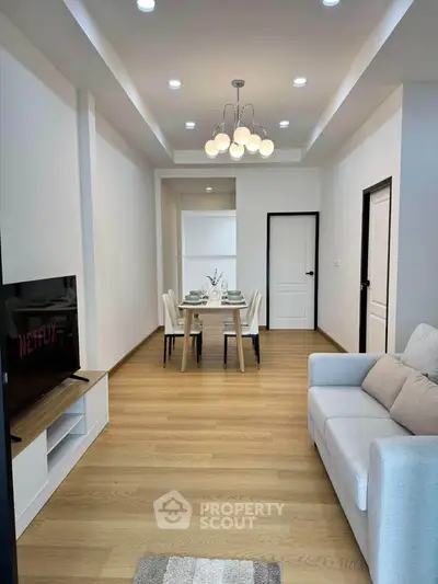 Modern living room with elegant dining area and stylish lighting, featuring a cozy sofa and sleek TV setup.