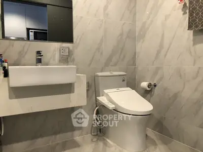 Modern bathroom with sleek marble tiles and high-tech toilet in a contemporary home.