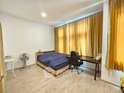 Spacious bedroom with modern decor and large windows for natural light.