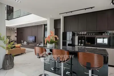 Luxurious modern kitchen with sleek black countertops and stylish bar stools in open-plan living area.