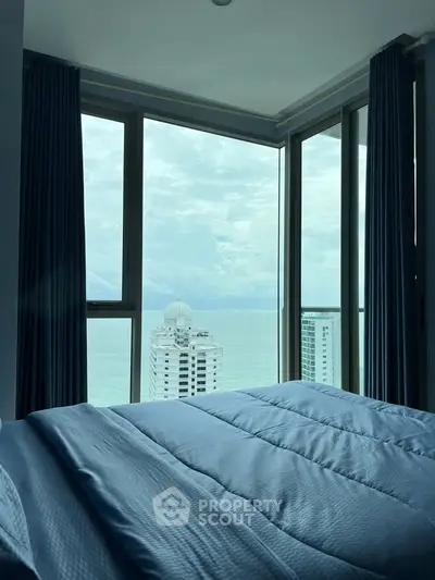 Luxurious bedroom with stunning ocean view and floor-to-ceiling windows in high-rise apartment.