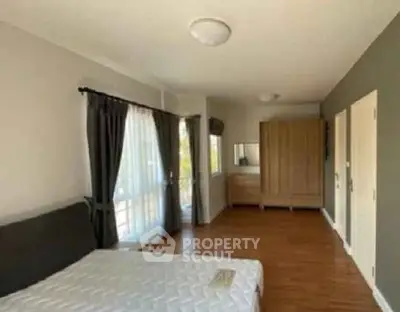 Spacious bedroom with large windows and wooden flooring